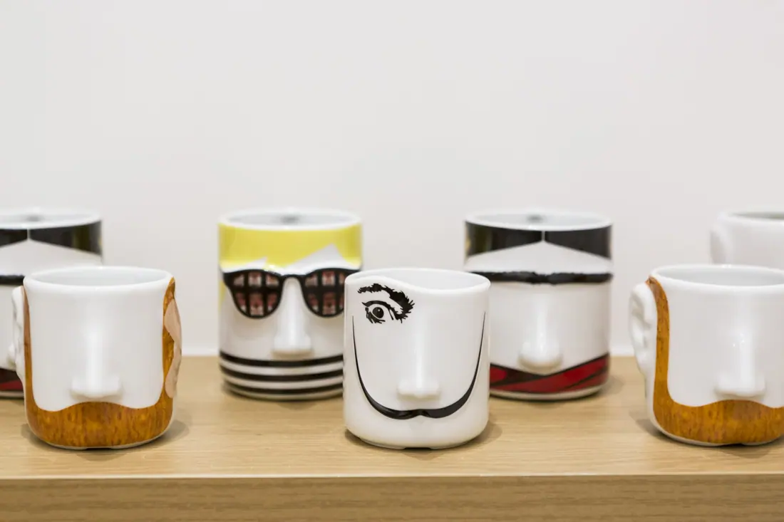 Tazas con caras dibujadas en una balda