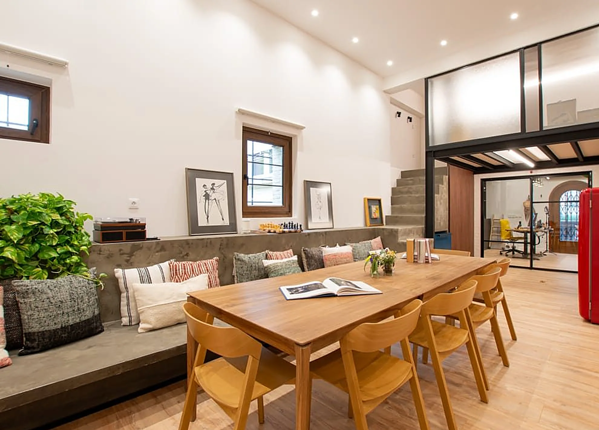 Sala con mesa larga de madera, banco con cojines y la escalera al fondo