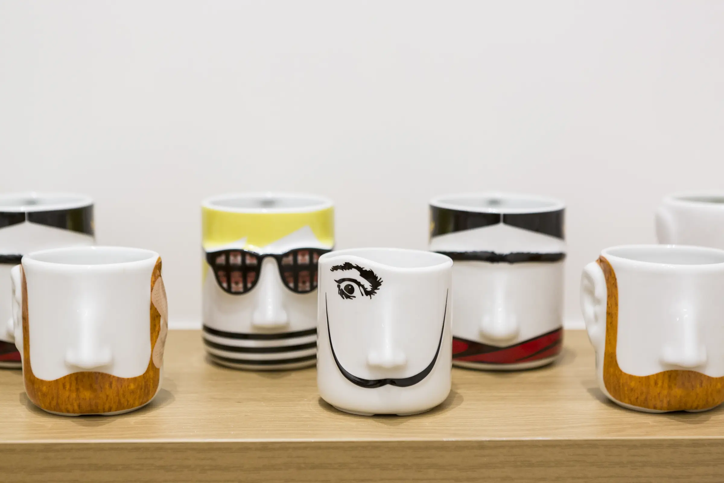 Tazas con caras dibujadas en una balda